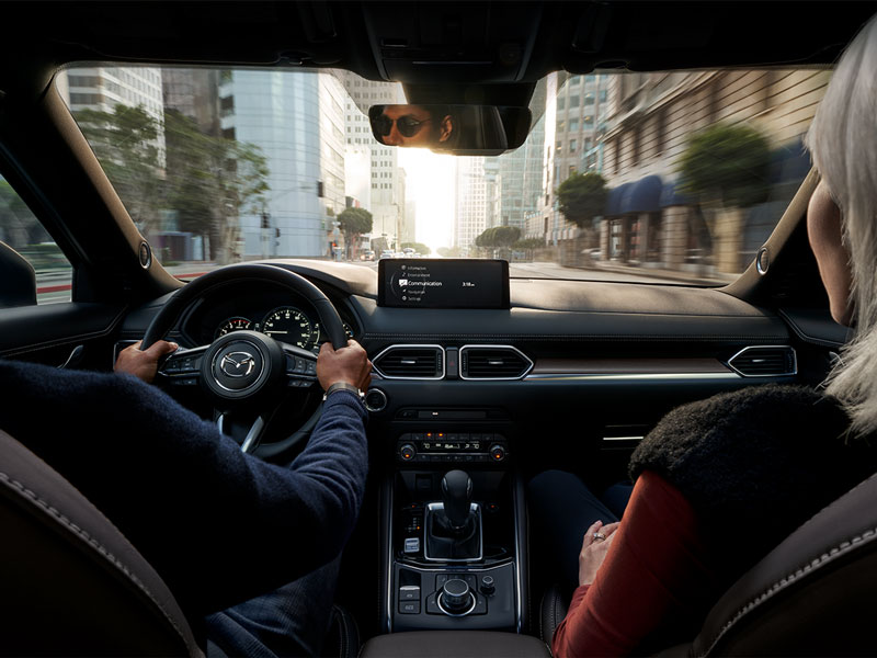 Interior of a Mazda vehicle as a couple drives down a city street