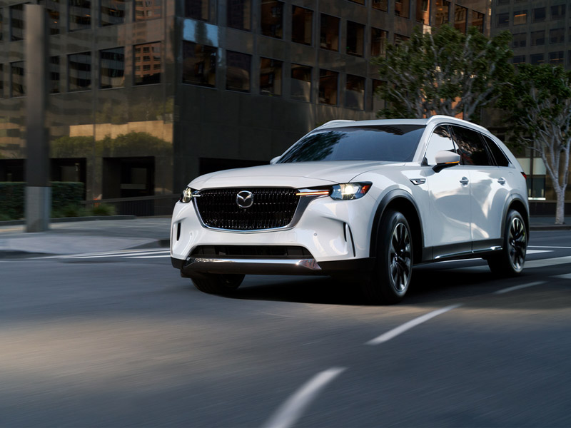 A white Mazda SUV driving through a city