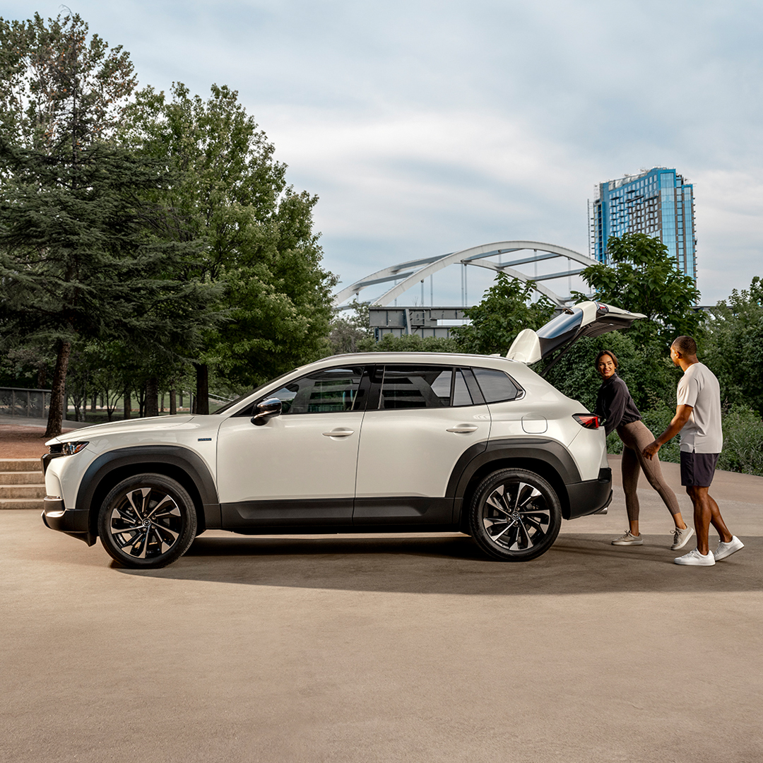 A couple packing a white Mazda CX-50 parked in a park
