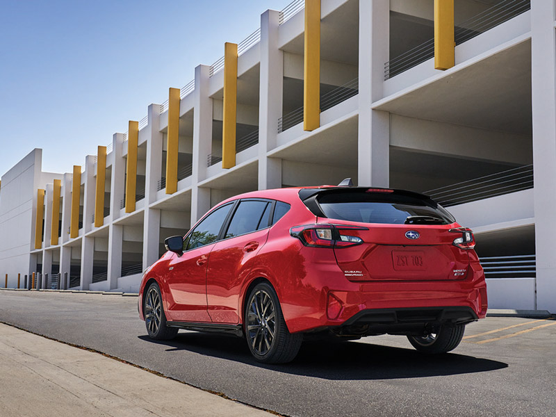 Back angle of a Subaru Impreza parked outside of a parking lot in the city