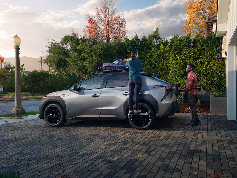 A Subaru Solterra parked in front of a garage while the family packs their Subaru vehicle