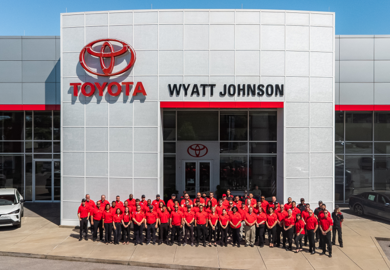 The Wyatt Johnson Toyota dealership storefront with employees standing outside all dressed in red.