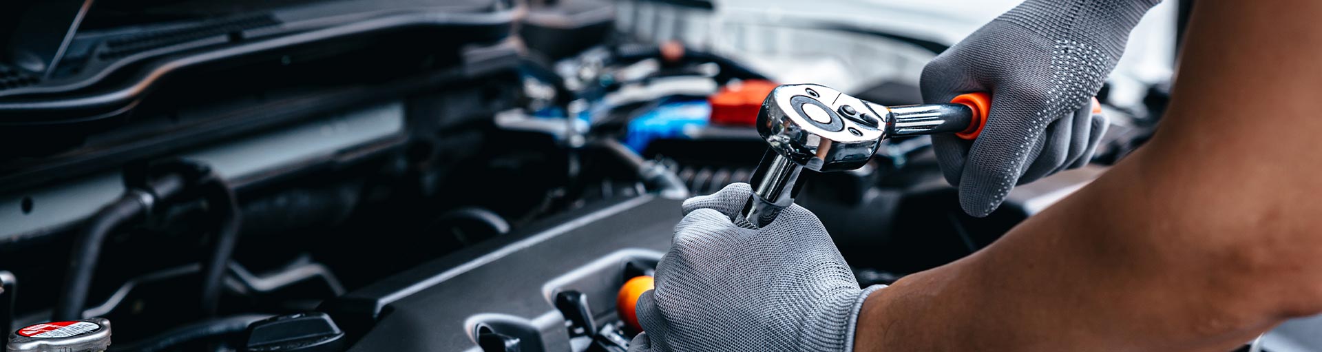 Close-up of a technician's hands and tools working on a vehicle engine