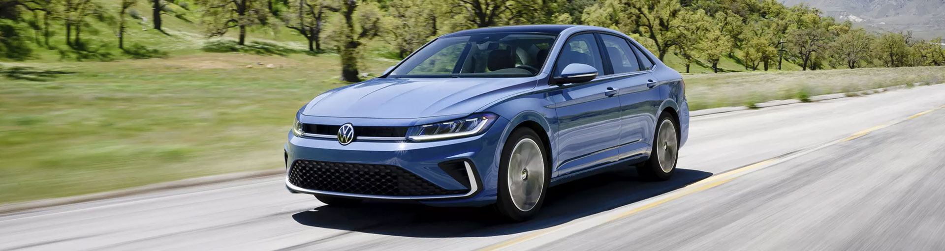 A Volkswagen Jetta compact sedan driving down a road