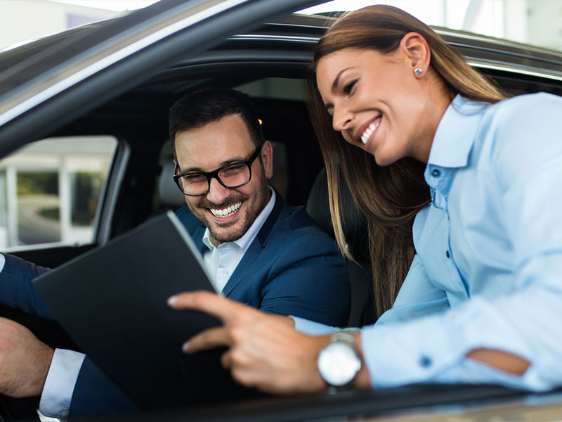 A salesperson and customer looking at a deal while the customer sits in the vehicle