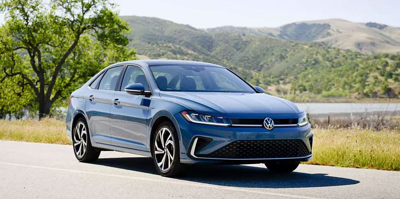 Volkswagen Jetta parked on a road by a lake during the day.
