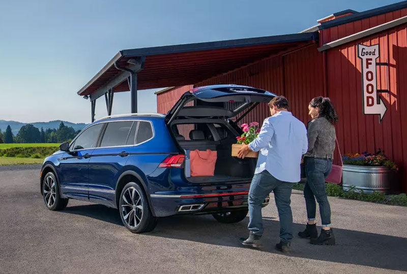 Two people loading groceries into the back of their Volkswagen Tiguan