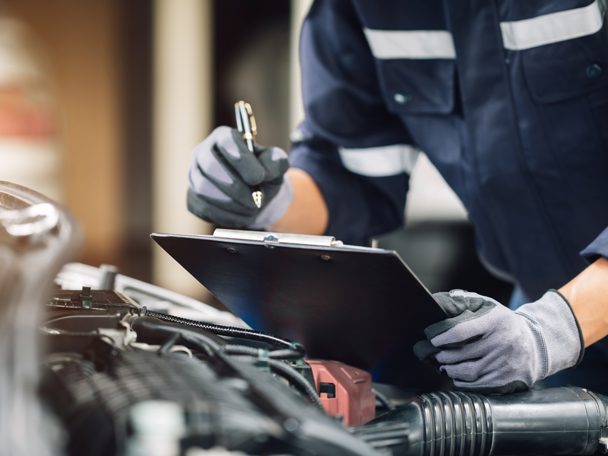 Close-up of a service technician holding a clipboard while performing an inspection.