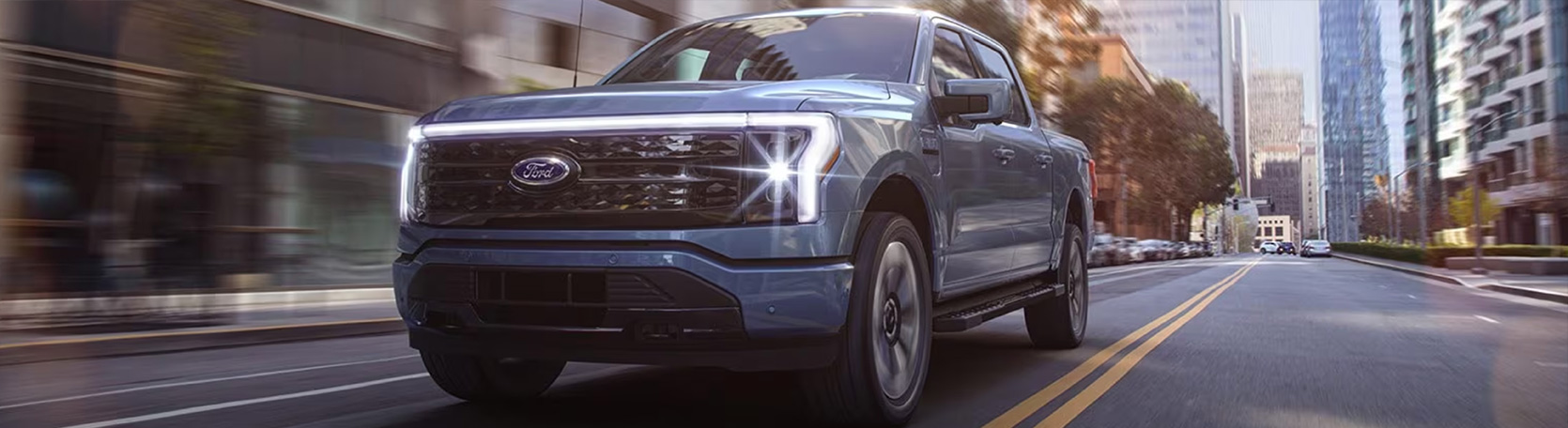 The 2023 Ford F-150 Lightning parked outdoors with a camper attached and the front trunk space open.